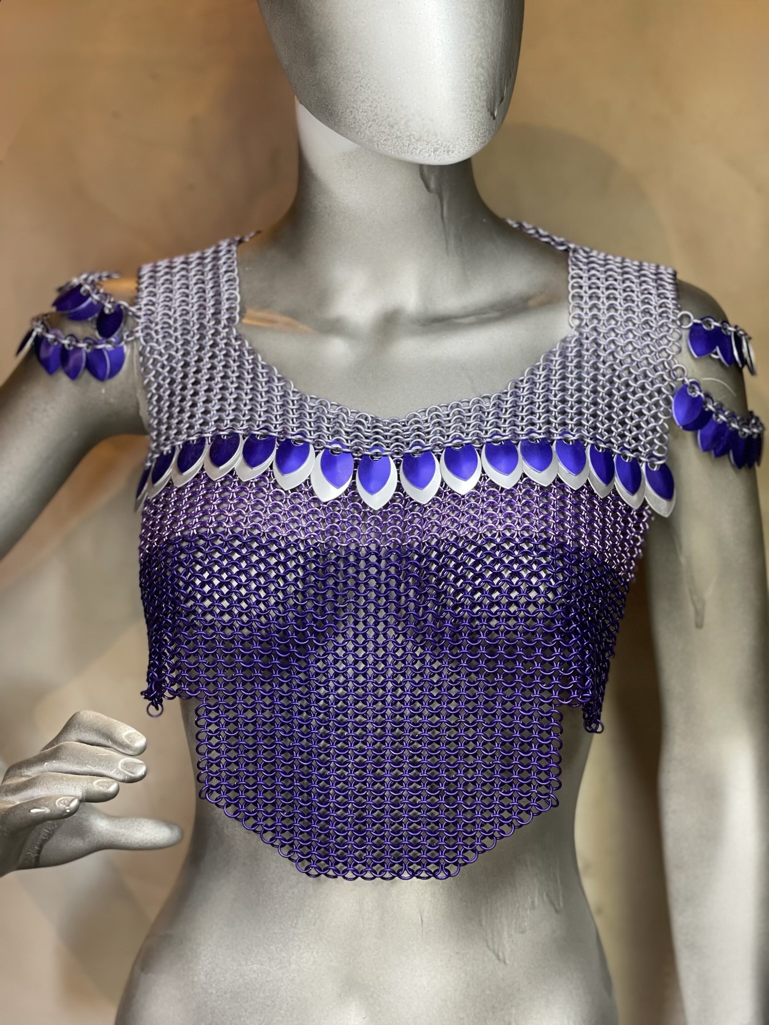 Viking woman with long blonde hair wearing lavender and silver chainmaille with purple scales. 
